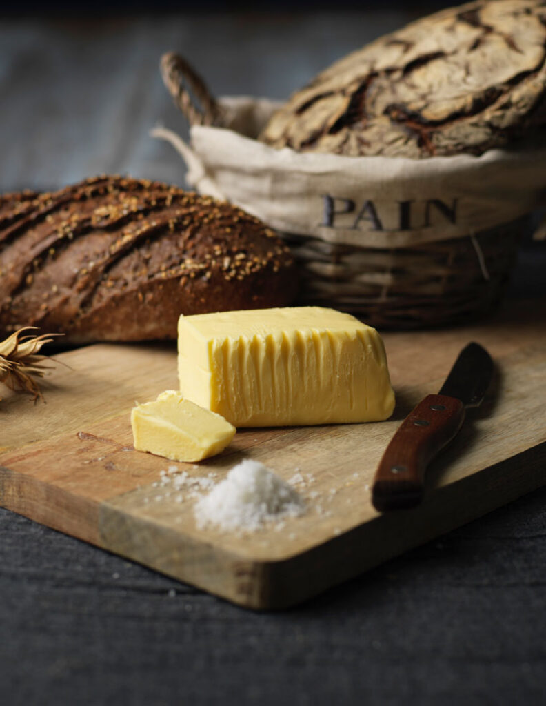 Fabrication du beurre de tradition : un beurre de baratte posé sur une planche près d'une panière de pain