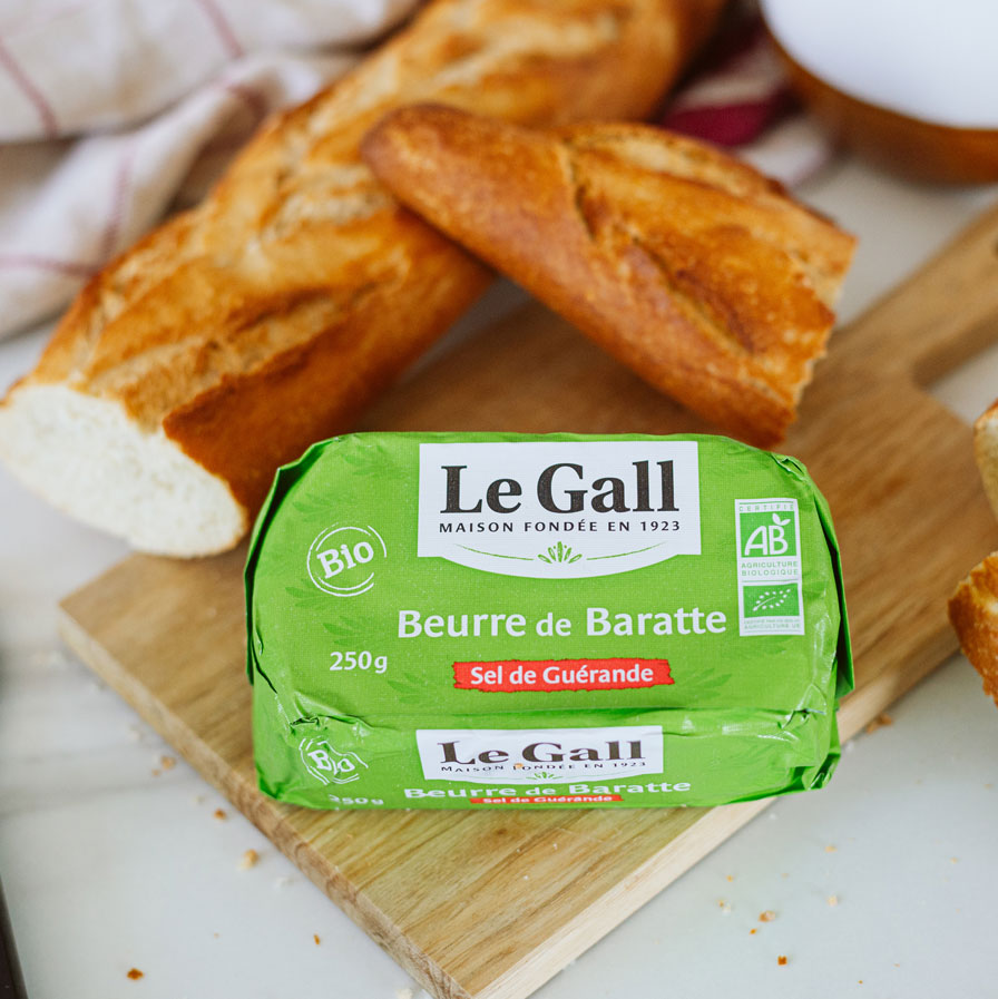 beurre de baratte biologique Le gall sur une planche à découper avec une baguette de pain tranchée.