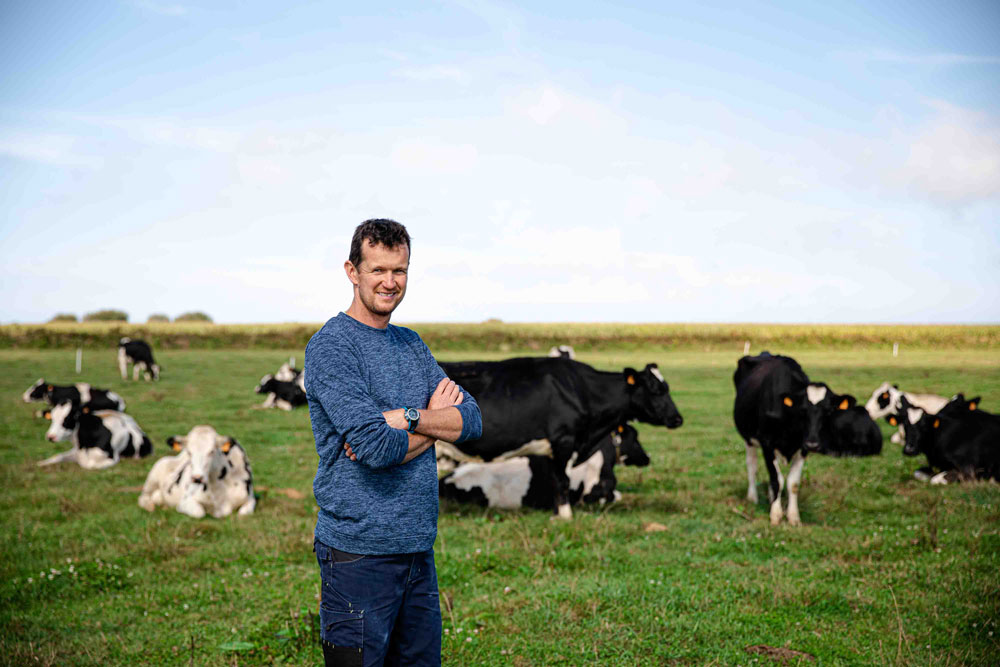 Un éleveur Le Gall pose debout dans un champ devant ses vaches laitières dans une exploitation du Finistère, à Bannalec. Le Gall est une laiterie engagée dans l'économie locale